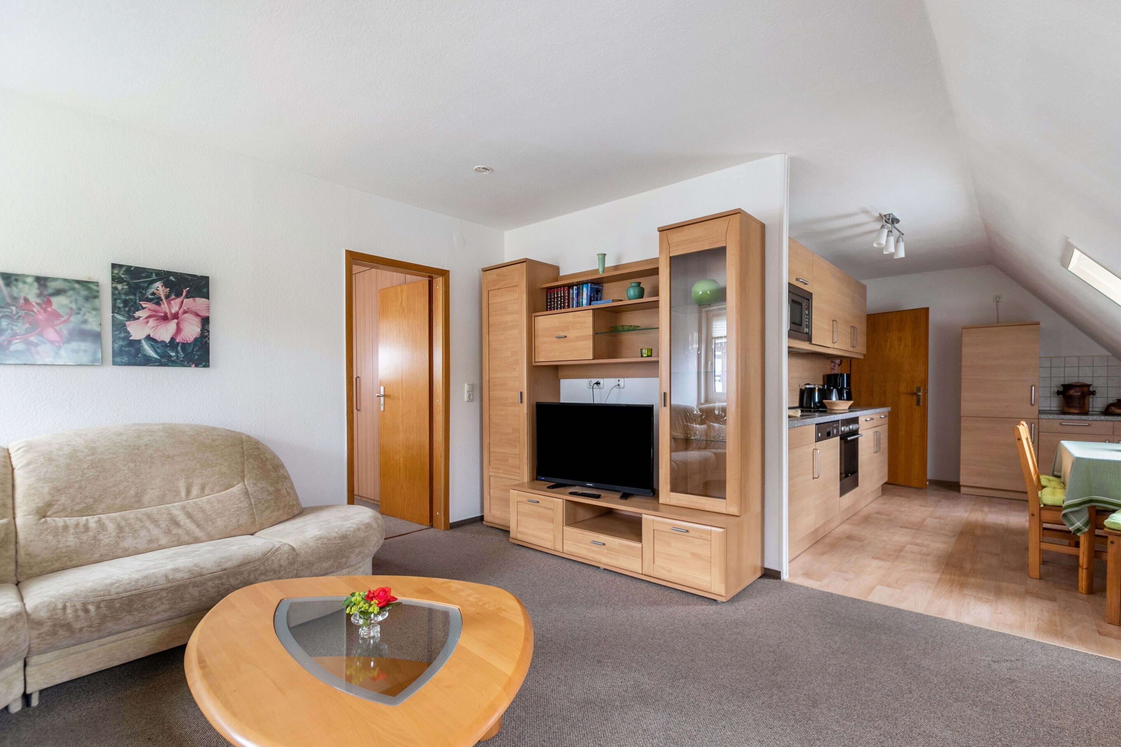 Un salon moderne comprenant un canapé, une table basse, un téléviseur, des meubles en bois et un coin cuisine.
