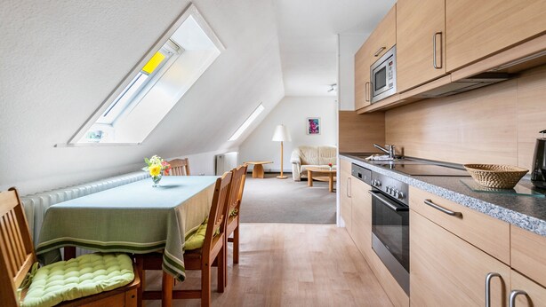 Eine moderne Küche mit Holzausstattung, einem Essbereich mit Tisch und Stühlen sowie einem Oberlicht.