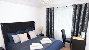 Una habitación de hotel moderna con una cama grande, un escritorio y una araña.
