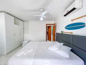 Een hotelkamer met een bed, een plafondventilator, een airconditioning en een deur naar een andere kamer.