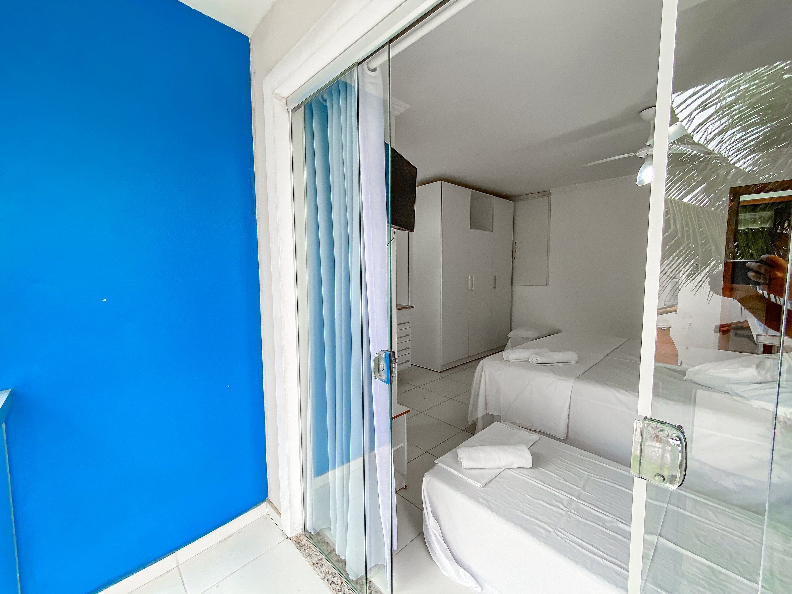 A bedroom with a bed, a wardrobe, and a bathroom visible through a glass door.