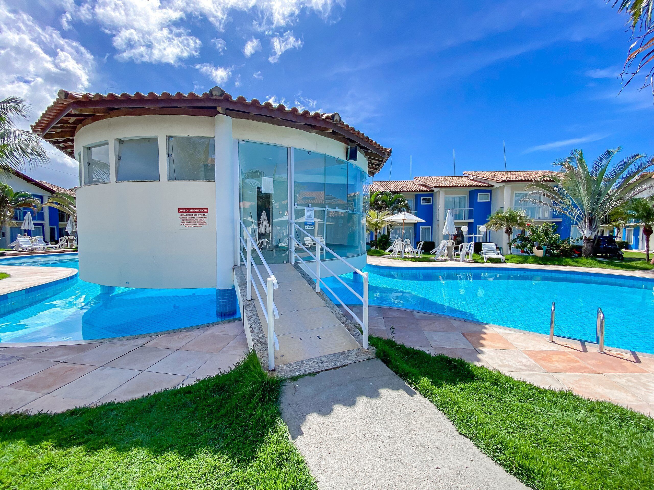 A pool area with a lifeguard station, lounge chairs, and a clear sky.