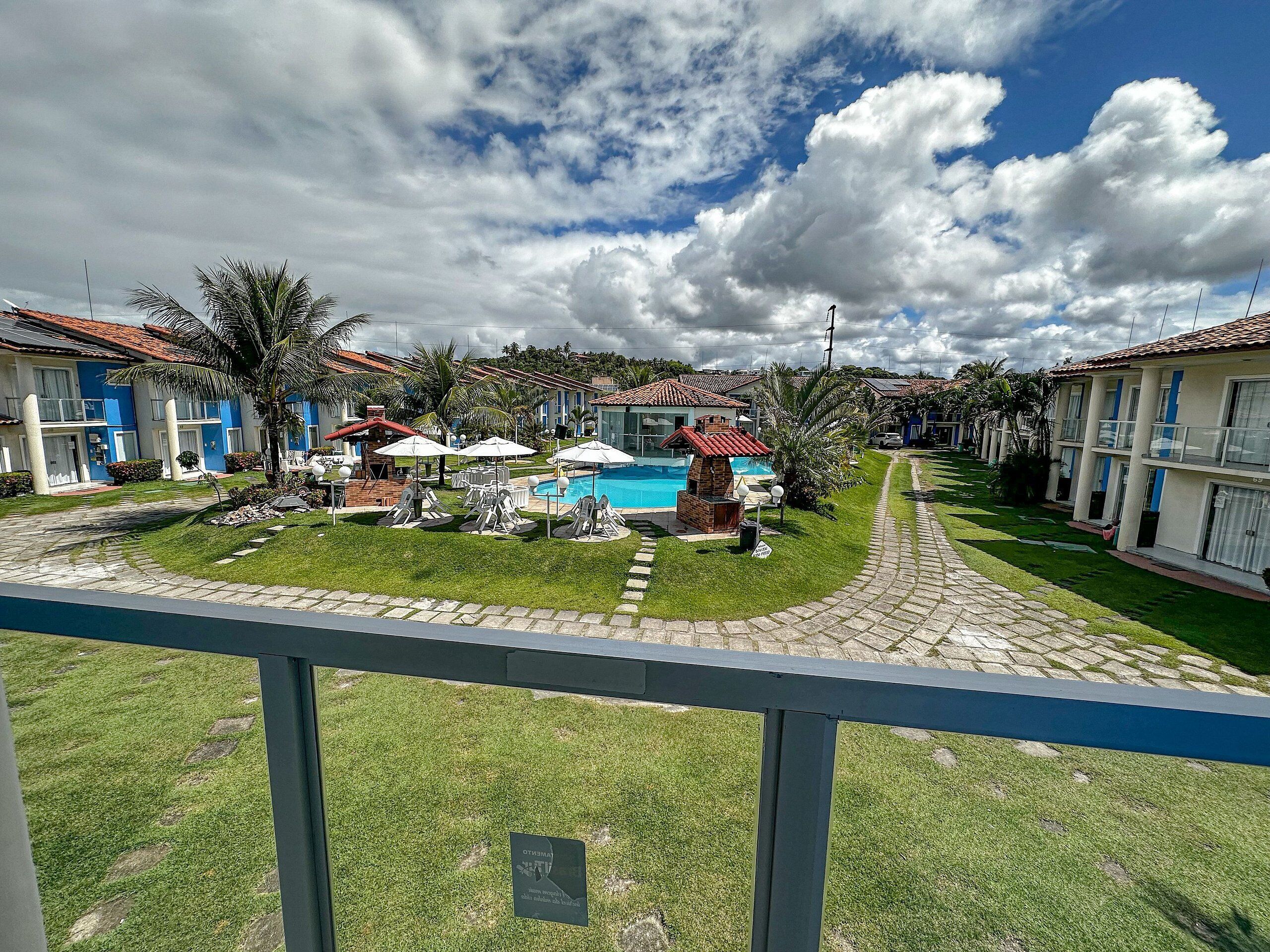 A hotel with a swimming pool, outdoor seating, and a well-maintained lawn.