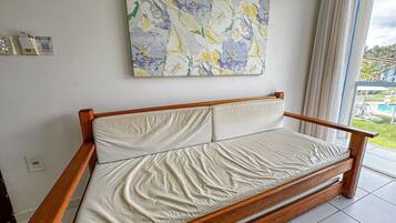Un divano in legno con un cuscino, un codice QR appeso al muro e un quadro floreale.