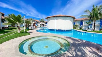 A swimming pool with a circular design, surrounded by palm trees and a clear blue sky.