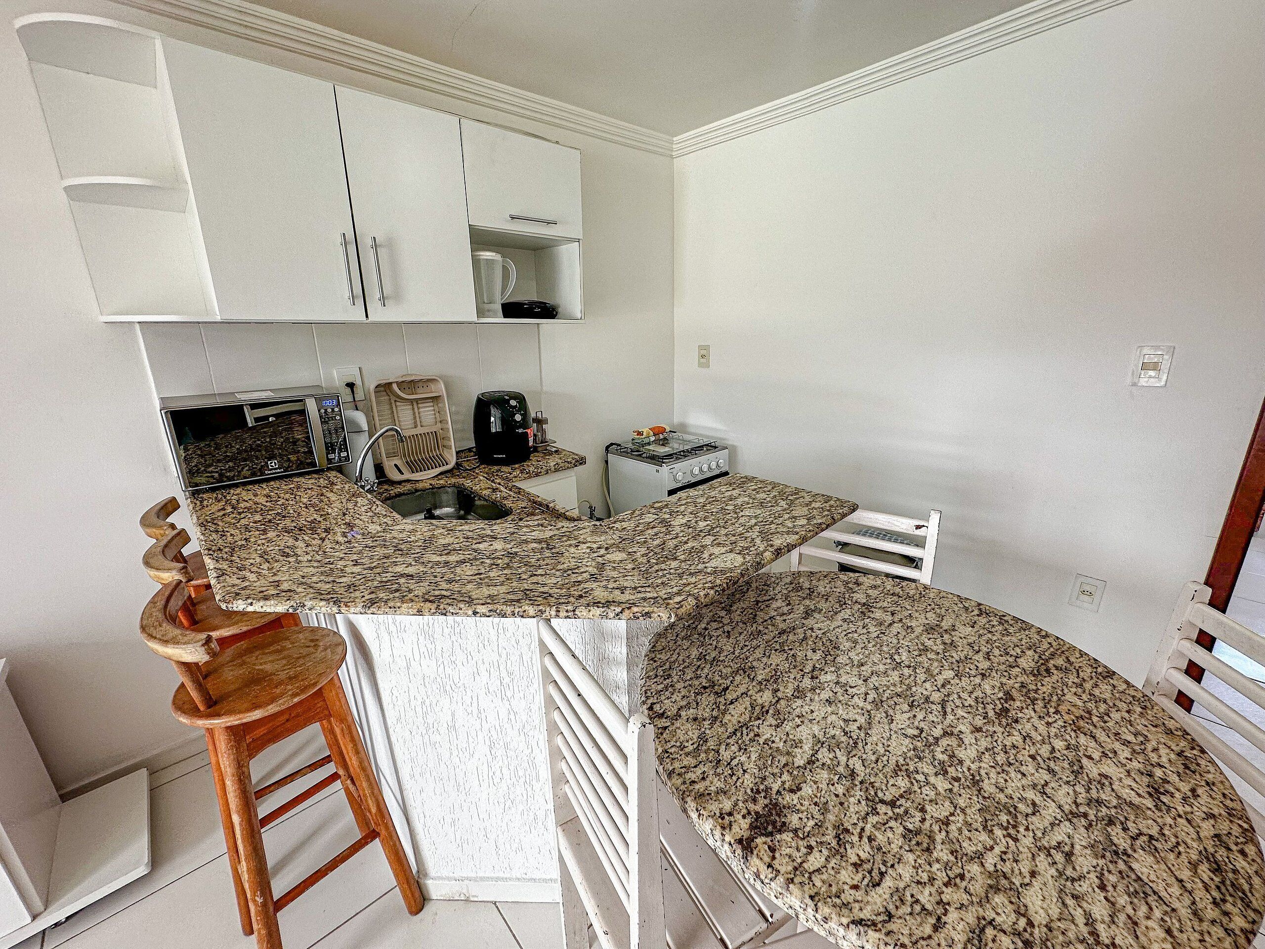 A compact kitchen with a granite countertop, a built-in oven, and a coffee maker.