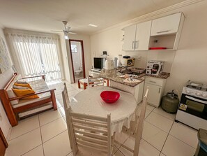 Una cocina compacta con comedor, ventilador de techo y vista al baño contiguo.