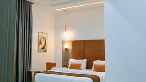 A modern hotel room with a large bed, a desk, and a painting on the wall. - Wellington Blu hotel & Suites (Enugu)