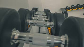 A row of black dumbbells with yellow accents on a rack.