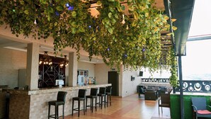 A bar area with a counter, bar stools, and a view of the city. - Wellington Blu hotel & Suites (Enugu)