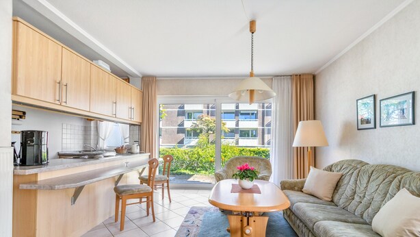 Un espacio habitable compacto con kitchenette, comedor y sofá.