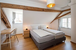 A bedroom with a loft-style ceiling, a desk, and two beds. - Haus Spiegel - Penthouse with roof terrace - Time out (Lindau (Bodensee))