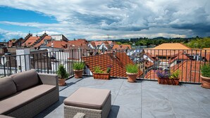 Eine Dachterrasse mit Gartenmöbeln, Kübelpflanzen und Blick auf die Stadt.