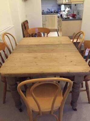 Una mesa de comedor con sillas, una cocina al fondo y una ventana.