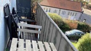 Una escalera exterior estrecha con escalones de madera y barandillas de metal.
