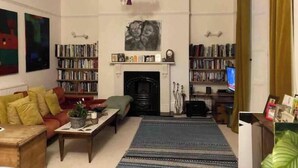 Una sala de estar con chimenea, estanterías, un sofá y una televisión.