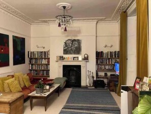 Una sala de estar con chimenea, estanterías, un sofá y una televisión.