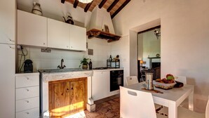 Una cocina con armarios blancos, encimera de madera, mesa de comedor con sillas y salpicadero de azulejos.