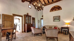 Un interior rústico con una mesa de comedor de madera, sillas, un aparador y una araña.