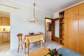 A dining area with a table, chairs, a hanging lamp, and a bookshelf. - Apartment 'Nr 02' with Wi-Fi (Büsum)