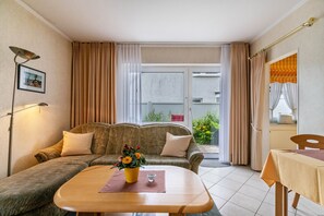 A modern living room with a sofa, a coffee table, a lamp, and a view of the outside. - Apartment 'Nr 02' with Wi-Fi (Büsum)