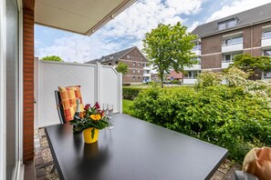 Et udendørs spiseområde med et bord, stole og en blomsterdekoration.