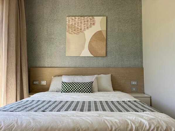 A hotel room with a bed, a headboard, a wall-mounted artwork, and a nightstand. - Fouka North Coast SA-8A-G03 (Marsa Matrouh)