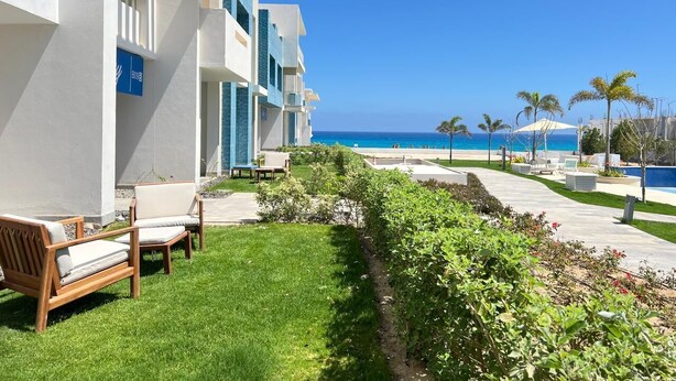 A hotel with a pool, outdoor seating, and a view of the ocean. - Fouka North Coast SA-8A-G03 (Marsa Matrouh)