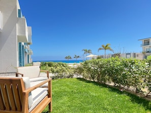 A hotel balcony with a view of the ocean, a grassy area, and a wooden chair. - Fouka North Coast SA-8A-G03 (Marsa Matrouh)