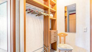 Un baño con estanterías de madera, un perchero con toallas florales, una silla y un espejo.