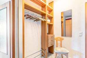 A bathroom with wooden shelving, a towel rack with floral towels, a chair, and a mirror. - Apartment 'Nr 03' with Wi-Fi (Büsum)