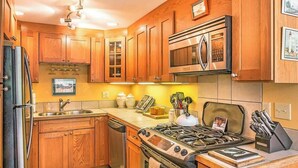 Una cocina con armarios de madera, un refrigerador de acero inoxidable, un microondas, una estufa y un lavaplatos.