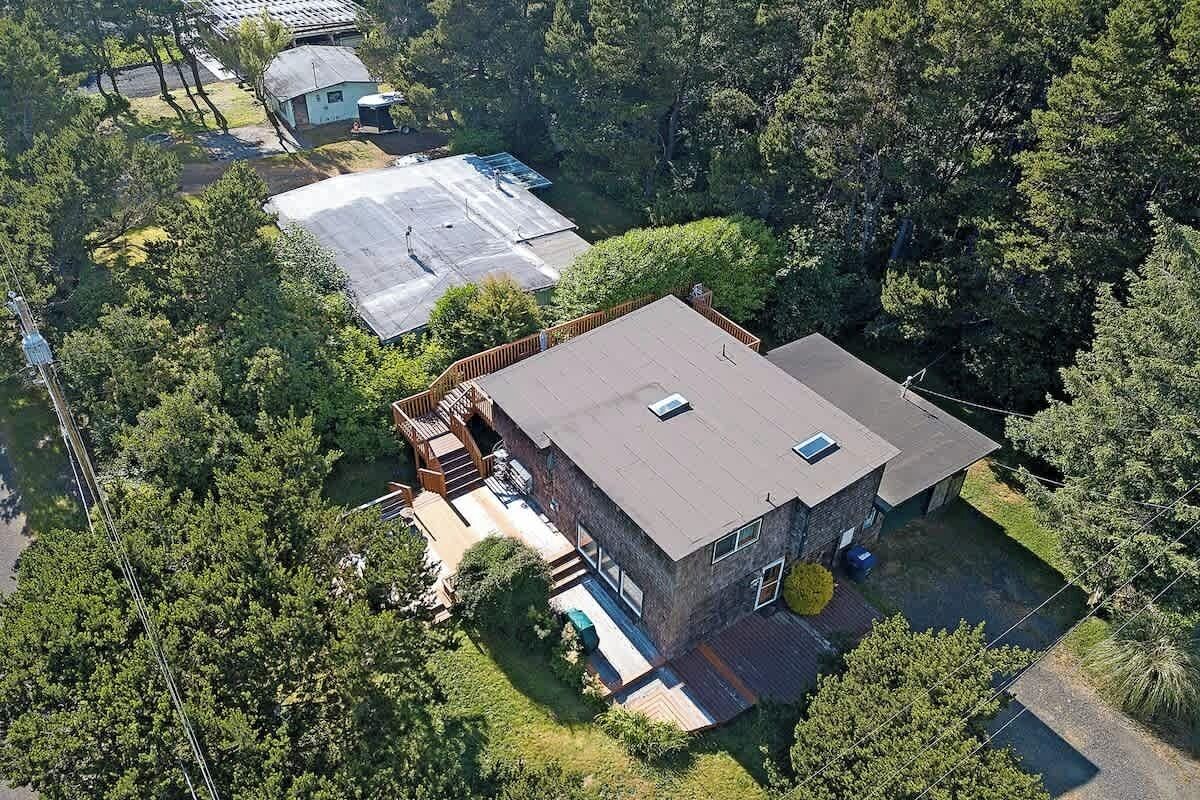 A modern two-story house with a flat roof, surrounded by dense trees.
