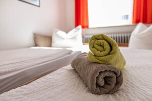 A neatly made bed with a rolled towel and a pillow. - Apartment 'Nr 06' with Wi-Fi (Büsum)