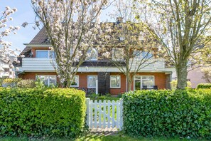 A two-story house with a brick facade, a white picket fence, and a well-maintained garden. - Apartment 'Nr 06' with Wi-Fi (Büsum)