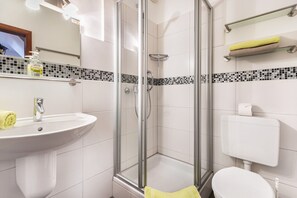 A bathroom with a glass-enclosed shower, a sink with a mirror, and a toilet. - Apartment 'Nr 06' with Wi-Fi (Büsum)