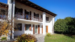 A two-story building with a balcony, a stone pathway, and a well-maintained lawn.