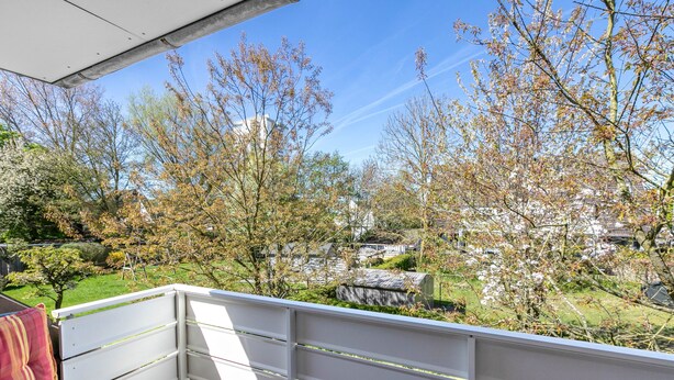 Ein Balkon mit Blick auf einen Garten und Gebäude.