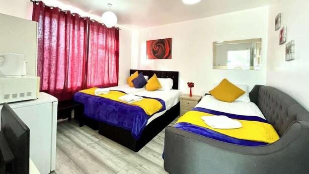 Ein Hotelzimmer mit zwei Betten, einem Schreibtisch, einem Stuhl, einem Spiegel und einem roten Vorhang.