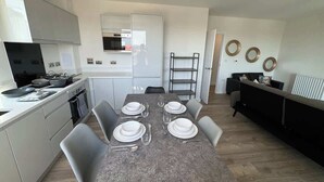 Une cuisine moderne équipée d’une table à manger pour quatre personnes, d’un four encastré et d’un réfrigérateur.
