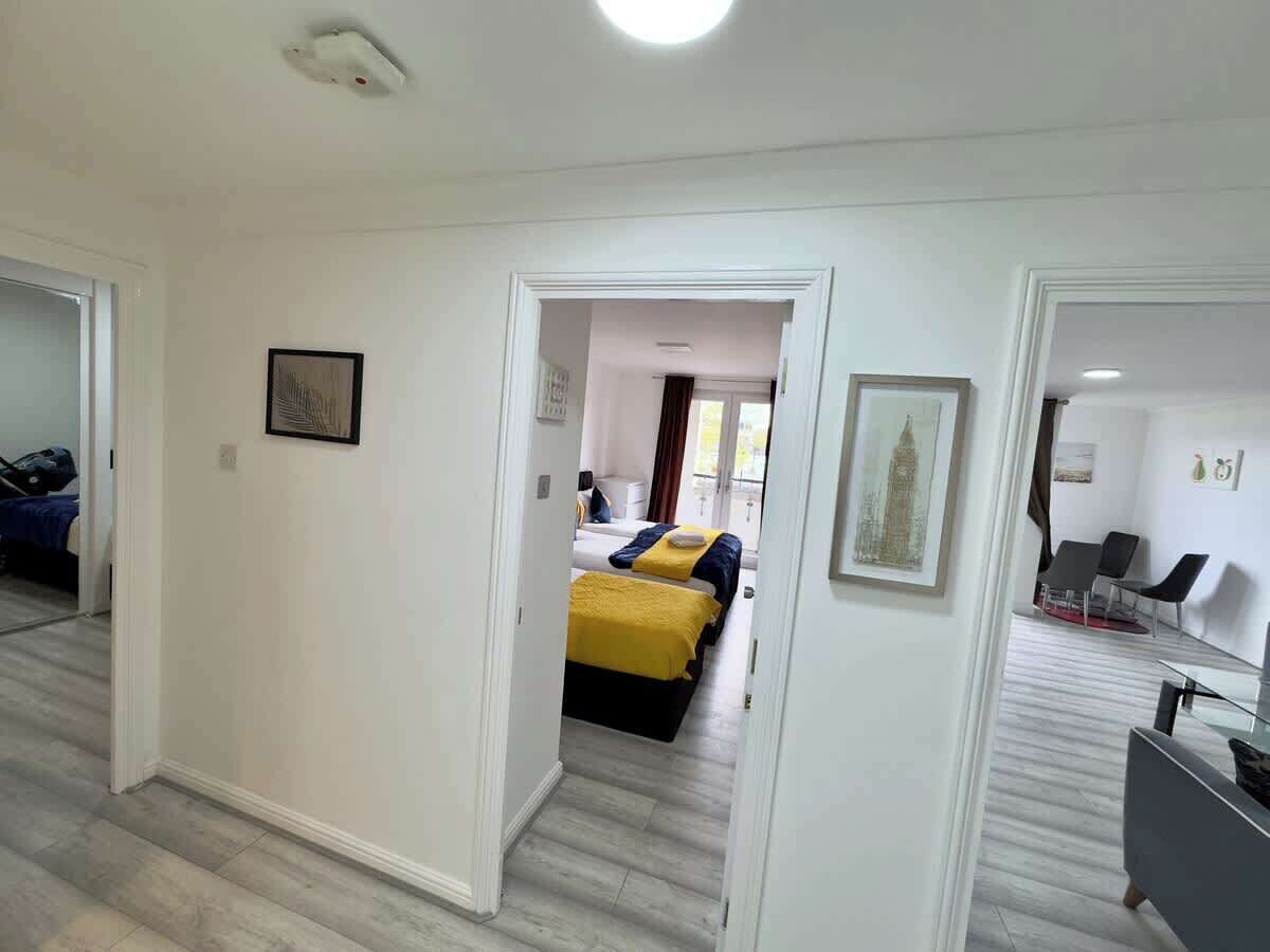 Ein Hotelzimmer mit Bett, Schreibtisch und Stuhl. Ein Flur führt zu einem weiteren Zimmer.