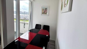 A room with a glass table, two chairs, a framed picture, and a window with a view. - Riverview Stunning Apartment 3Bedroom 2Bathroom (Greater London)