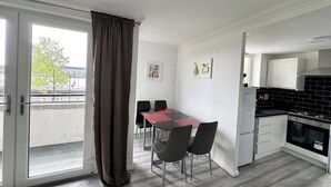 A modern apartment with a dining area, kitchen, and large sliding glass doors to a balcony. - Riverview Stunning Apartment 3Bedroom 2Bathroom (Greater London)