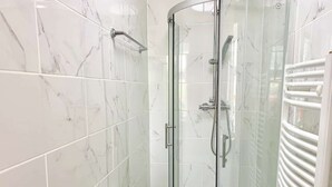 Un bagno con box doccia in vetro, un water e un portasciugamani.