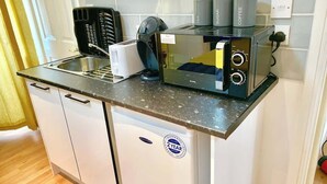 Una cucina compatta con macchina da caffè integrata, tostapane e frigorifero.