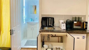 Una cucina compatta con lavello, tostapane, microonde e frigorifero di due anni.