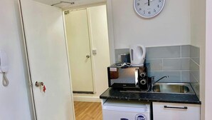 Una cocina compacta con microondas, hervidor y pileta.