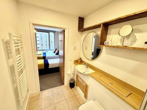 Une salle de bain avec un lavabo, un miroir et une étagère en bois.
