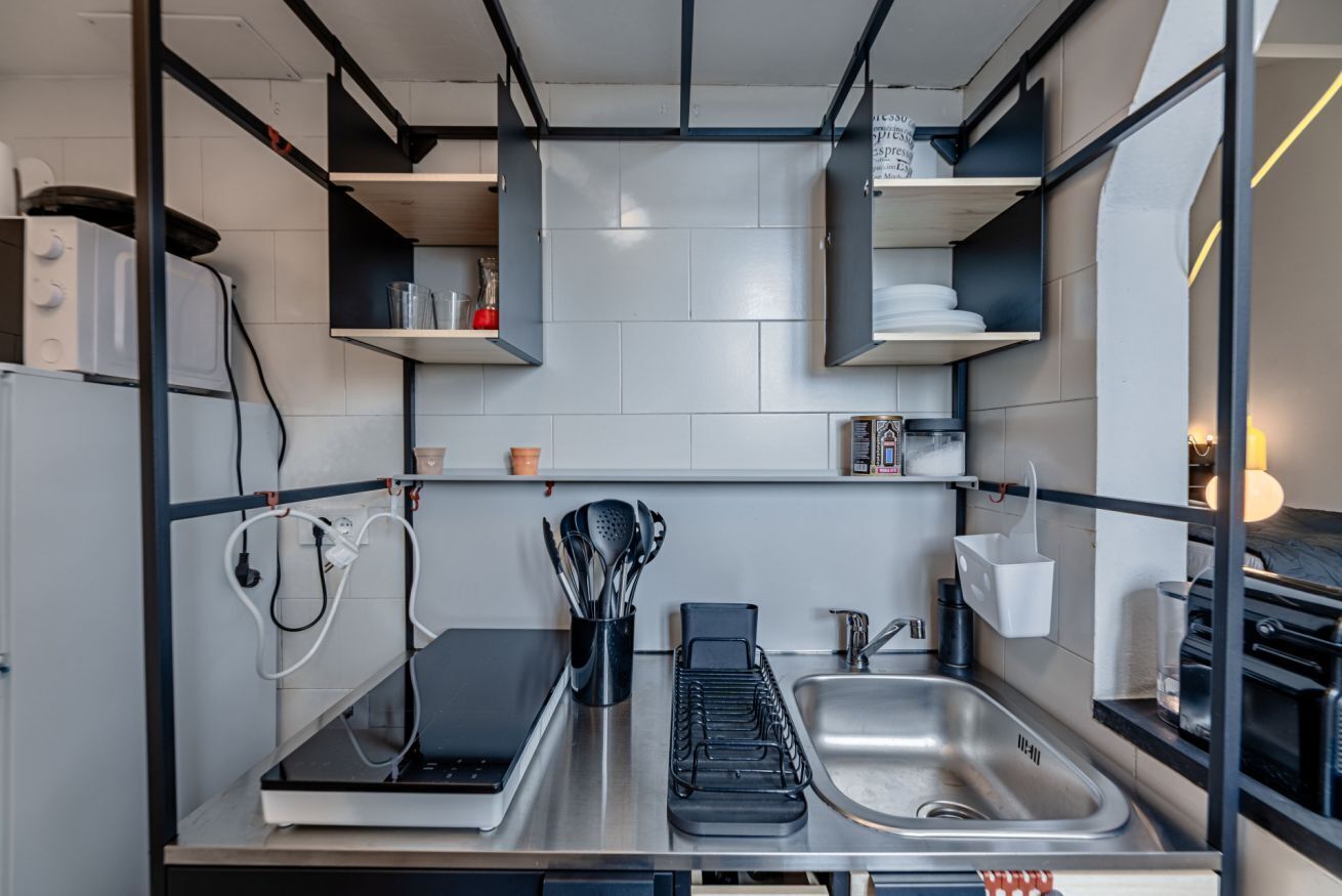A modern kitchen with a built-in stove, a sink, and a countertop with a coffee machine and utensils.