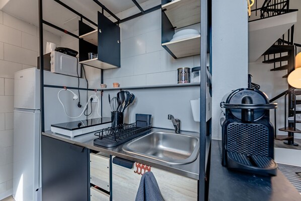 A compact kitchen with a built-in microwave, a sink, and a compact stove.